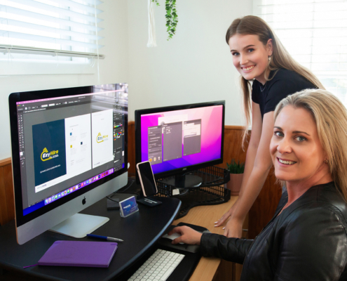 Merge Media lenaing over computers smiling while working